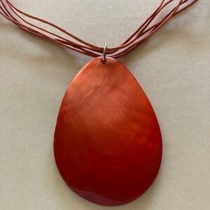 Variegated orange glass pendant on a leather necklace.